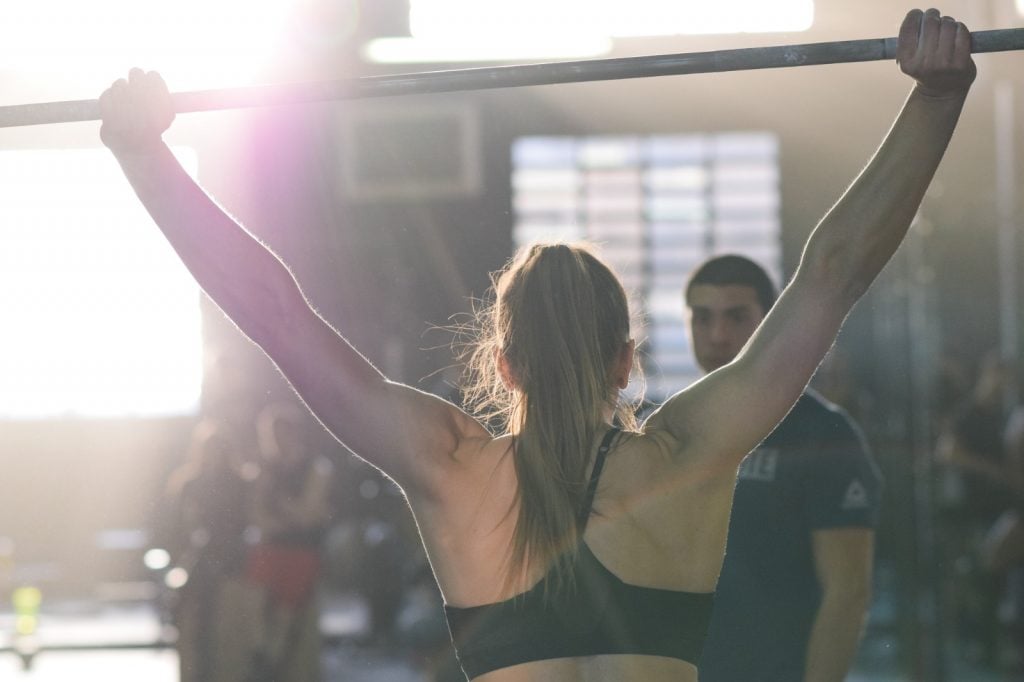 Atleta di crossfit, vista di spalle, si allena con il bilanciere