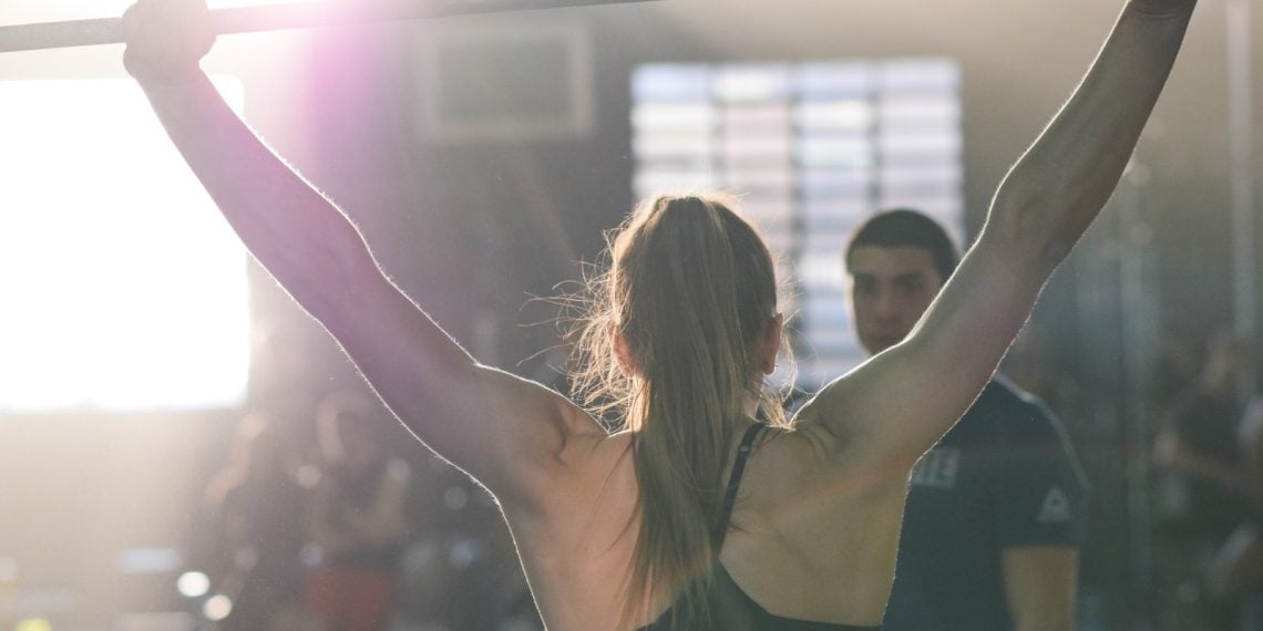 Atleta di crossfit, vista di spalle, si allena con il bilanciere
