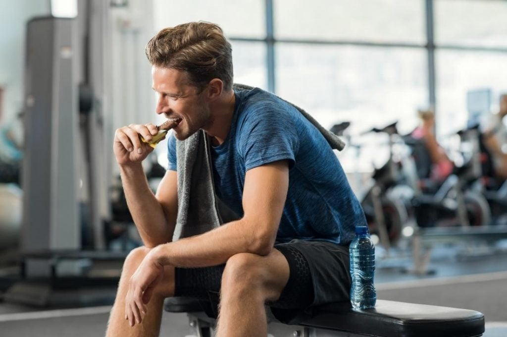 sportivo che consuma una barretta energetica e proteica dopo l'allenamento