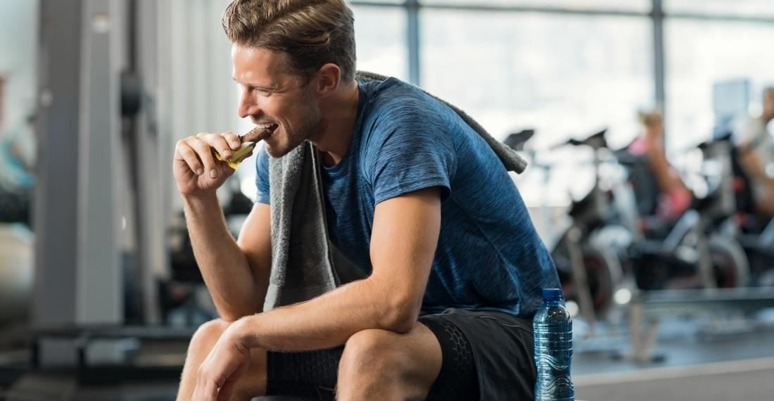sportivo che consuma una barretta energetica e proteica dopo l'allenamento